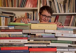 Petra Meyer linst hinter einem Bücherstapel hervor